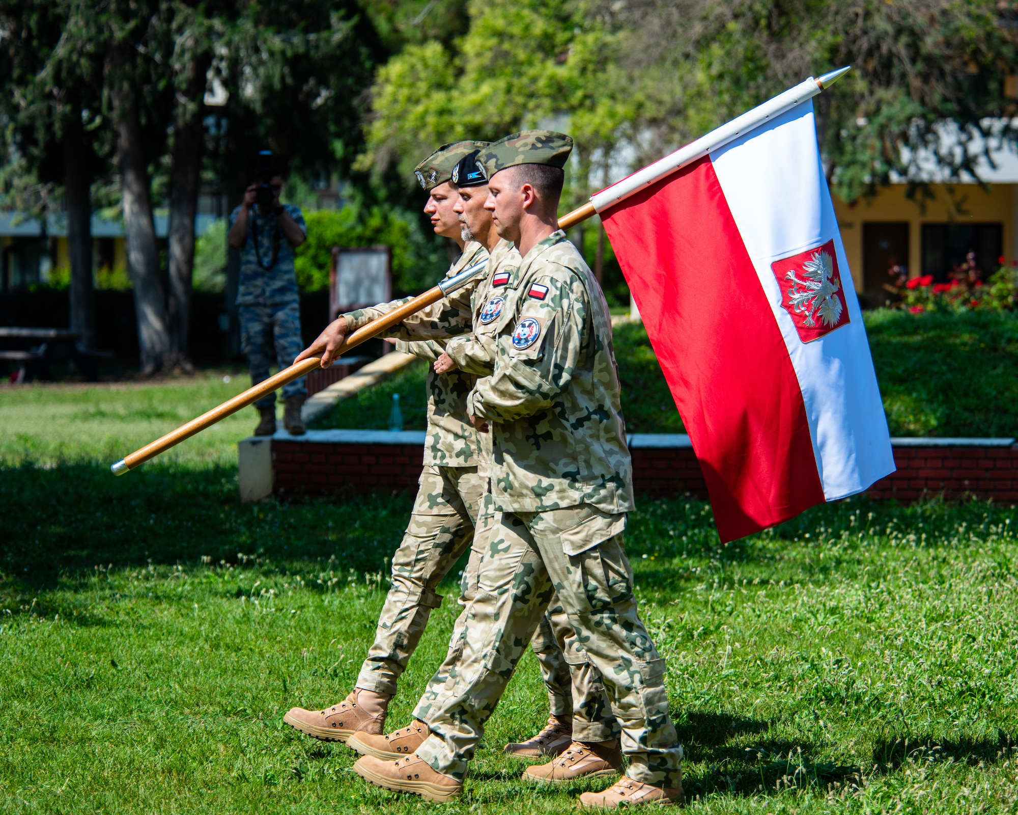 Polish military members march with the Polish flag