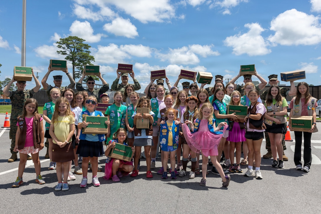 U.S. service members and Girl Scouts North Carolina Coastal Pines members pose for a group photo during an Operation Cookie Drop delivery at Marine Corps Air Station Cherry Point, North Carolina, May 20, 2026. Girl Scouts North Carolina Coastal Pines delivered 4,500 boxes of cookies to units aboard MCAS Cherry Point as part of Operation Cookie Drop, a community service project dedicated to showing appreciation to service members. (U.S. Marine Corps Photo by Lance Cpl. Dillon Anderson)