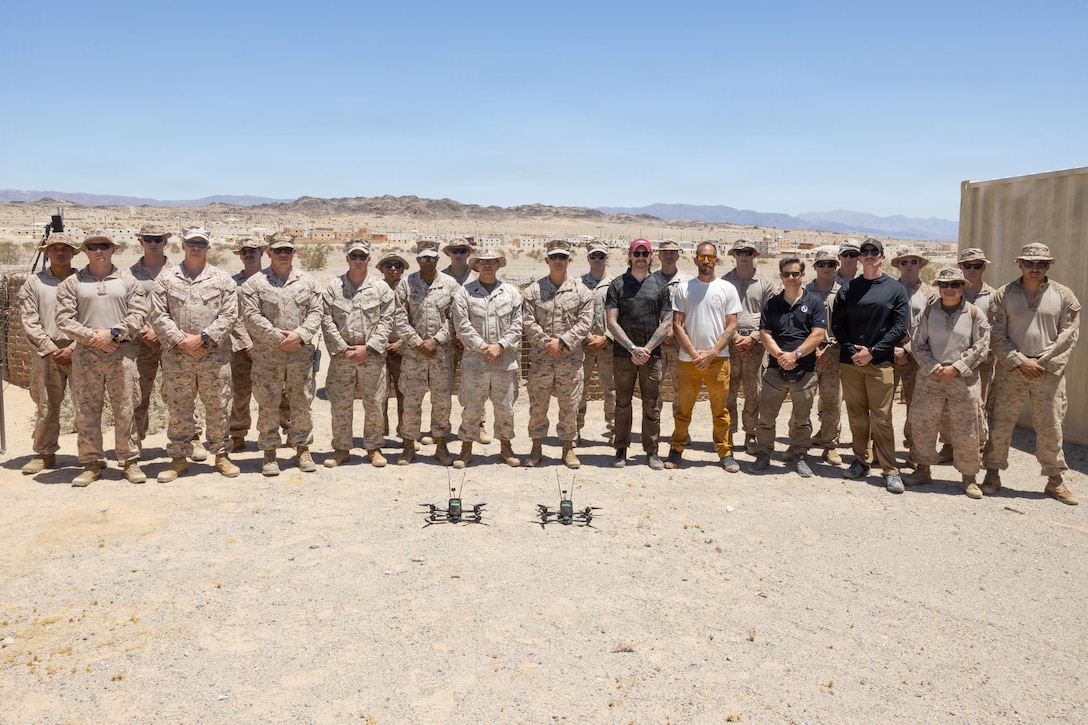 Instructors and students of Attack Drone Operator Course pose for a group photo at Range 100, Marine Corps Air Ground Combat Center, Twentynine Palms, California, May 21, 2026. Through intensive hands-on training, the course equips service members with tactical first-person view piloting skills, directly enhancing lethality and survivability in contested environments. (U.S. Marine Corps photo by Pfc. Ethan DePaul)