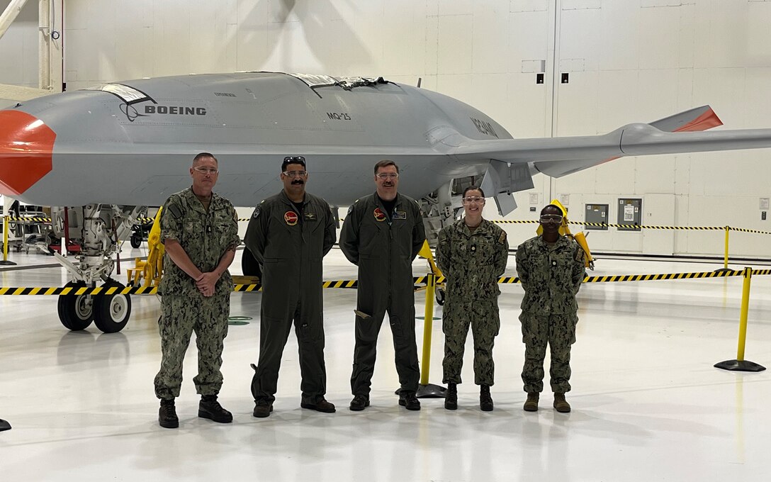 A group of male and female military personnel stand in front of an aircraft