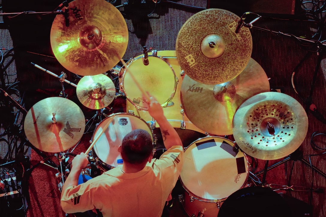 A Marine plays the drums in a dimly lit room as seen from above.