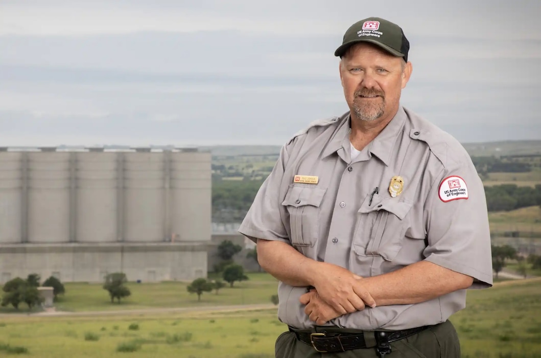 A man wearing a park ranger shirt and USACE hat smiles at the camera.
