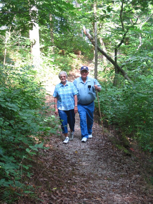 An older man and woman hiking a nature trail.