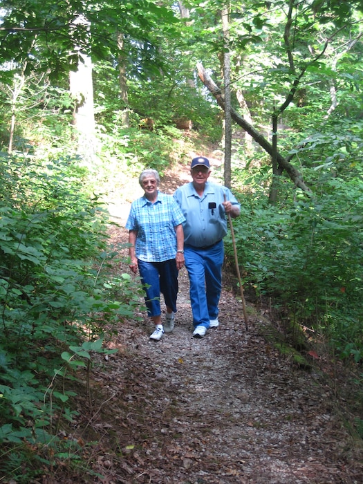 An older man and woman hiking a nature trail.