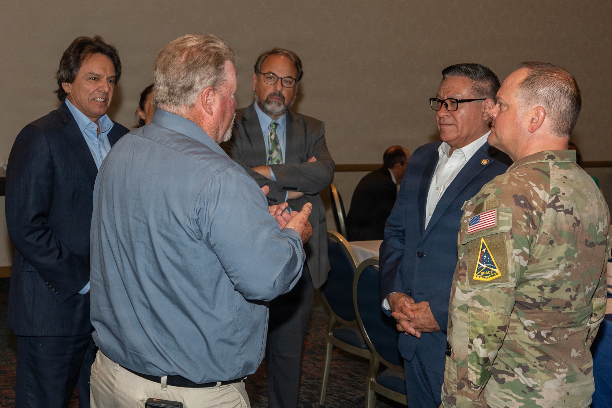 A group of five people stand and speak to each other.