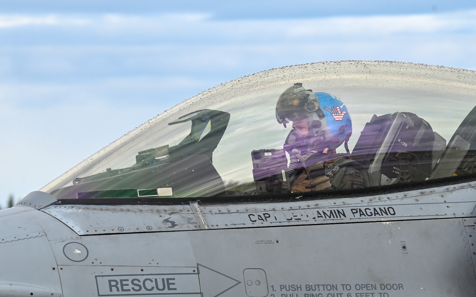 A U.S. Air Force pilot for the F-16 Fighting Falcon, assigned to the 51st Fighter Wing from Osan Air Base, Republic of Korea, gives their unit’s heritage hand sign on the flightline at Eielson Air Force Base, Alaska, June 1, 2026.