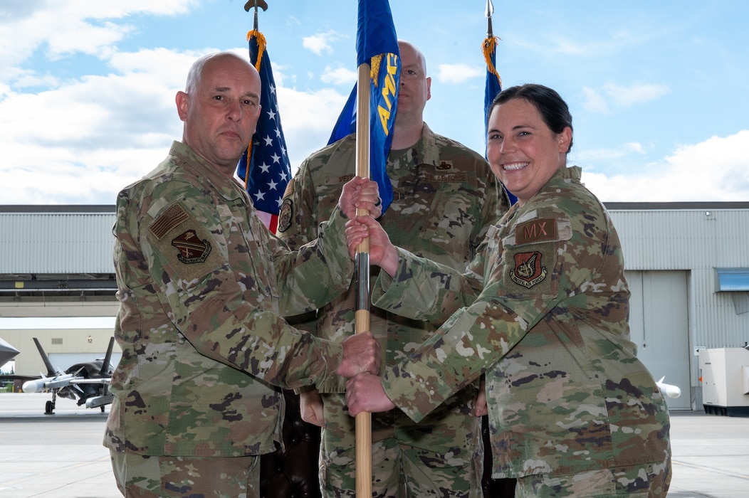 U.S. Air Force Col. Joseph Gilpin, left, 354th Maintenance Group commander, passes a guidon to Maj. Renee Bohac, incoming 354th Aircraft Maintenance Squadron commander, during the 354th AMXS activation ceremony on Eielson Air Force Base, Alaska, June 1, 2026.