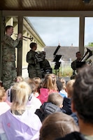 U.S. Airmen with the Five Star Brass, U.S. Air Forces in Europe, Air Forces Africa Band, play music for school children during a musical exchange at the Ecole Primaire Les Hauts Champs in Carentan-les-Marais, France, June 2, 2026. The exchange highlights our shared values of free cultural expression while building a connection between U.S. service members and a new generation in Normandy. From June 2-7, 2026, more than 600 U.S. Soldiers, Sailors, Marines, Guardians and Airmen from roughly 17 units historically linked to D-Day made up Joint Task Force 82 and participated in over 90 commemorative events throughout the Normandy Region. (U.S. Army National Guard photo by 1st Sgt. HollyAnn Nicom)