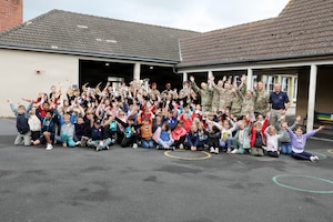 U.S. Airmen with the Five Star Brass, U.S. Air Forces in Europe, Air Forces Africa Band, and Soldiers with the 173rd Airborne Brigade pose for a photo alongside school children after a musical exchange at the Ecole Primaire Les Hauts Champs in Carentan-les-Marais, France, June 2, 2026. The exchange highlights our shared values of free cultural expression while building a connection between U.S. service members and a new generation in Normandy. From June 2-7, 2026, more than 600 U.S. Soldiers, Sailors, Marines, Guardians and Airmen from roughly 17 units historically linked to D-Day made up Joint Task Force 82 and participated in over 90 commemorative events throughout the Normandy Region. (U.S. Army National Guard photo by 1st Sgt. HollyAnn Nicom)