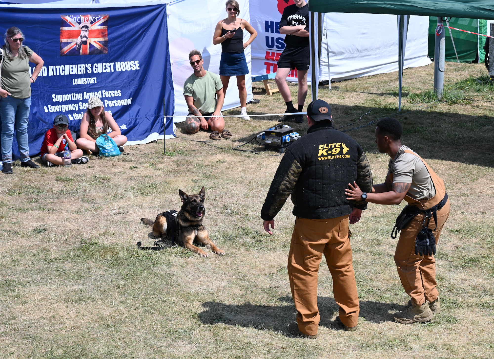 U.S. Air Force Staff Sgt. Thaddeus Huffin, right, 100th Security Forces Military Working Dog section handler, demonstrates a search on Staff Sgt. Charles Pope, 100th SFS MWD section kennel master, as MWD Juan acts as overwatch at the Suffolk Show in Ipswich, England, May 27, 2026. Juan, along with his handler and kennel master, performed two demonstrations during the first day of the event to highlight a small part of the K-9 ‘s capabilities. (U.S. Air Force photo by Karen Abeyasekere)