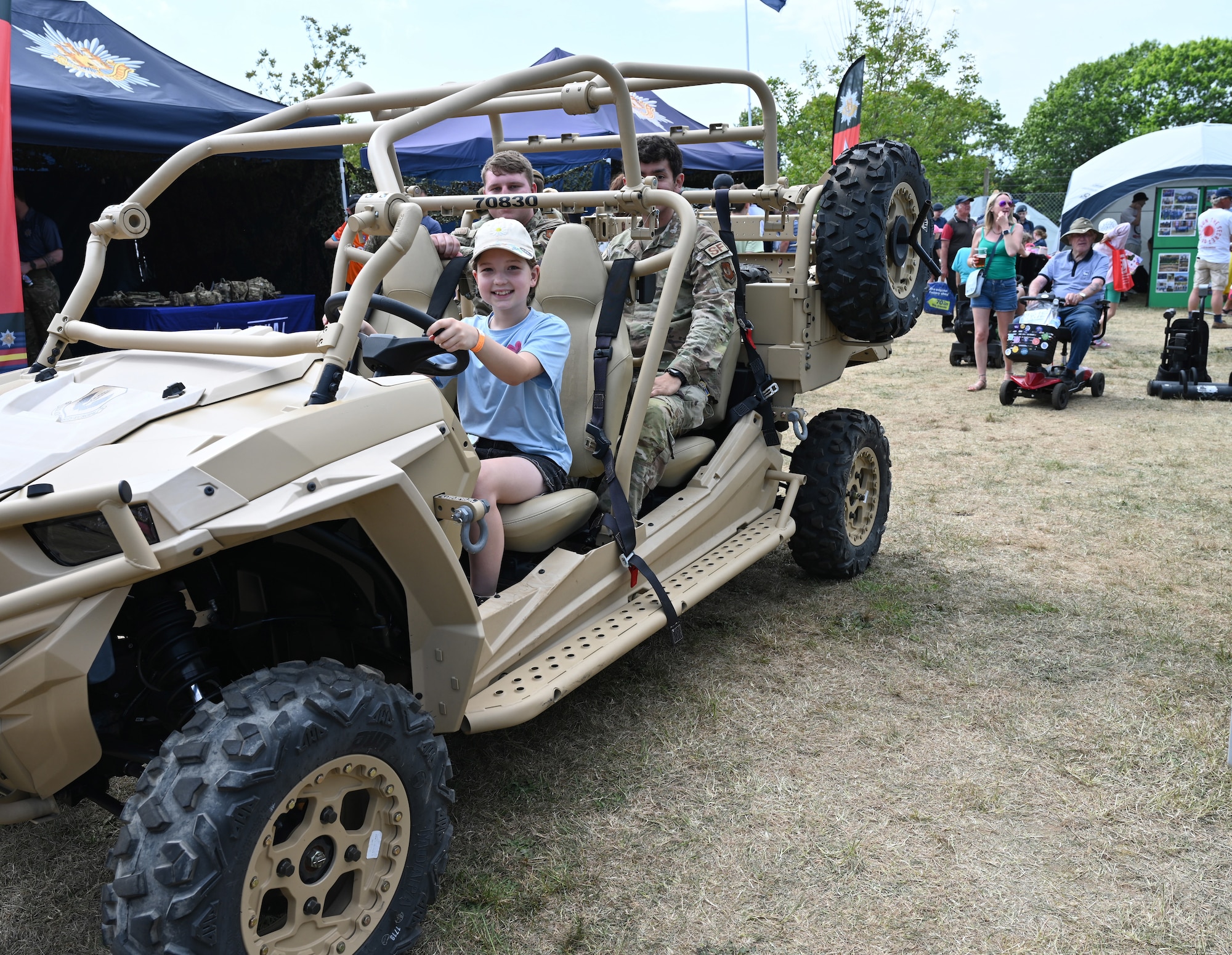 Isabel Fisk checks out a military utility vehicle with her “passengers,” U.S. Airmen 1st Class Ryan Melchers, top left, and Connor Chapple, both 100th Security Forces Squadron response force members, at the Suffolk Show in Ipswich, England, May 27, 2026. Airmen from RAF Mildenhall and RAF Lakenheath spent two days at the Suffolk Show showcasing their equipment and capabilities. The annual event celebrates Suffolk’s heritage, culture and industry. (U.S. Air Force photo by Karen Abeyasekere)