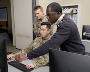 uniformed U.S. military and civilian work at a computer
