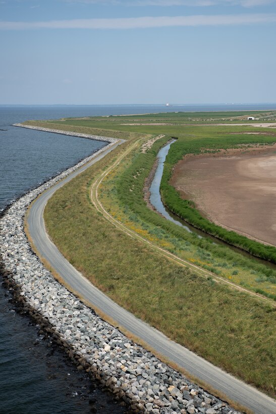 The winding shape of a green island landmass is visible from the air, separated from the water by a rocky shoreline.