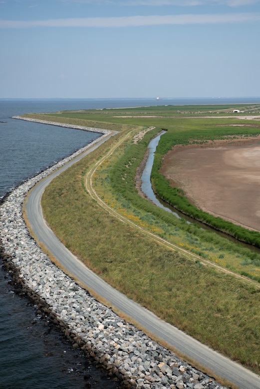 The winding shape of a green island landmass is visible from the air, separated from the water by a rocky shoreline.