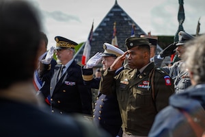U.S. Army Lt. Col. Earl Wilson, deputy staff judge advocate, Headquarters and Headquarters Battalion, 82nd Airborne Division, salutes during the playing of the national anthem at the Three Cemeteries Monument, Sainte-Mère-Église, France, June 2, 2026. The Three Cemeteries Monument honors the 14,000 U.S. troops, particularly from the 82nd Airborne Division, who fell during the battle to liberate Normandy, France. (U.S. Army photo by Staff Sgt. Catessa Palone)