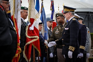 U.S. Army Lt. Col. Earl Wilson, deputy staff judge advocate, Headquarters and Headquarters Battalion, 82nd Airborne Division, shakes the hands of the French regimental flag bearers at the Three Cemeteries Monument, Sainte-Mère-Église, France, June 2, 2026. The Three Cemeteries Monument honors the 14,000 U.S. troops, particularly from the 82nd Airborne Division, who fell during the battle to liberate Normandy, France. (U.S. Army photo by Staff Sgt. Catessa Palone)