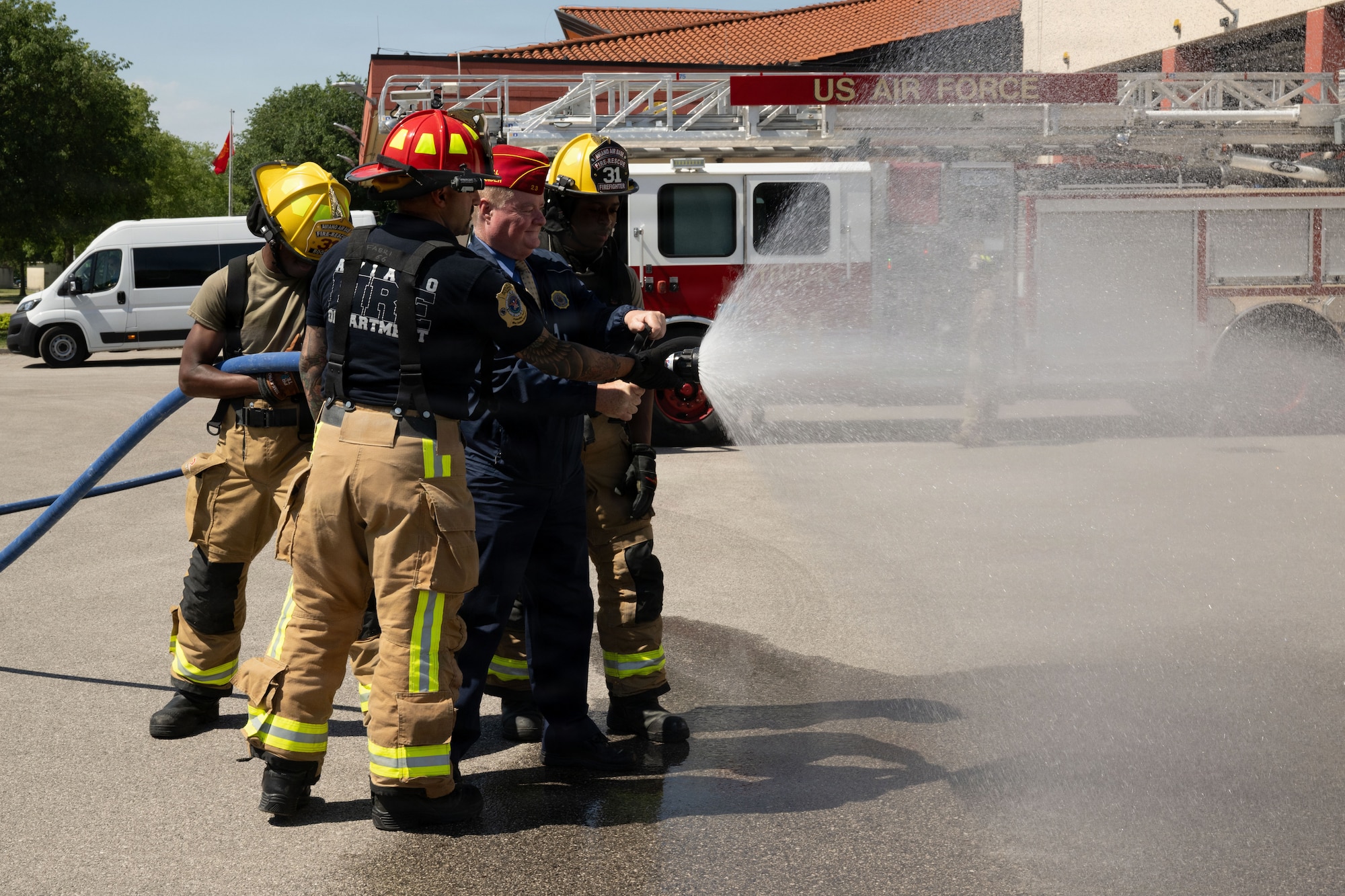 Firefighters and Commander Wiley sprays water with hose.