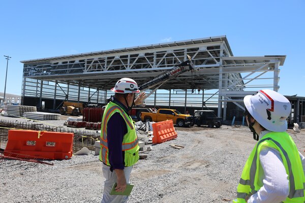 Picture of two men standing looking at a building being constructed.