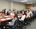 Graduates of the PALACE Acquire program watch a slideshow brief at Joint Base San Antonio-Lackland, Texas, April 27, 2026. The three-day event bridges the gap between formal training and real-world operations. (U.S. Air Force photo by Deirdre McNamara)
