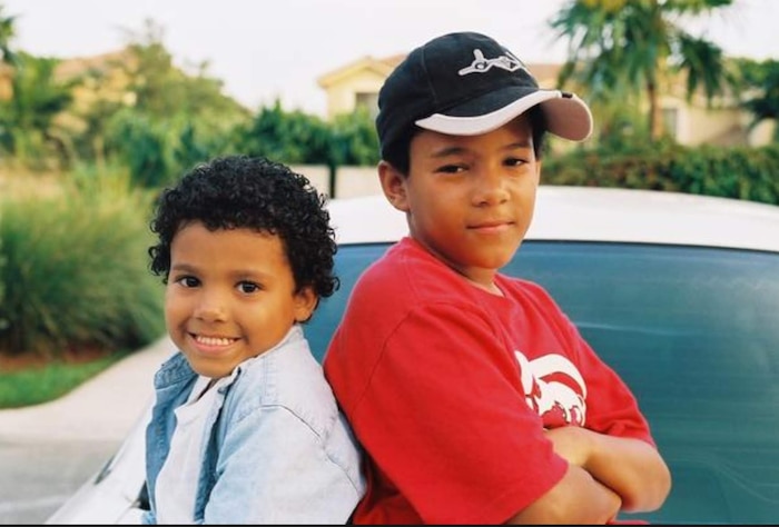 Two children back to back posing for a photo during childhood
