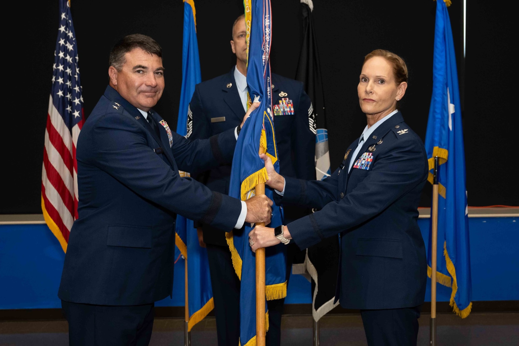 Air Force commander, passes the 37th Training Wing guidon to Col. Kellie S. Courtland, 37th TRW incoming commander, during the 37th TRW change of command ceremony at Joint Base San Antonio-Lackland, Texas, May 29, 2026. The change of command ceremony is a military tradition that allows unit members to see the outgoing commander depart and identify the incoming commander. (U.S. Air Force photo by Marcus Robins)