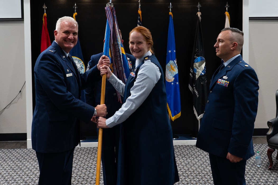 U.S. Air Force Maj. Kelly Griffith, outgoing 17th Comptroller Squadron commander, passes the 17th CPTS guidon to Col. Matthew Norton, 17th Training Wing commander, during a change of command ceremony at Goodfellow Air Force Base, Texas, June 2, 2026. The passing of the guidon is a military tradition that dates back to the time of Frederick the Great of Prussia. (U.S. Air Force photo by Senior Airman Brian Lummus)