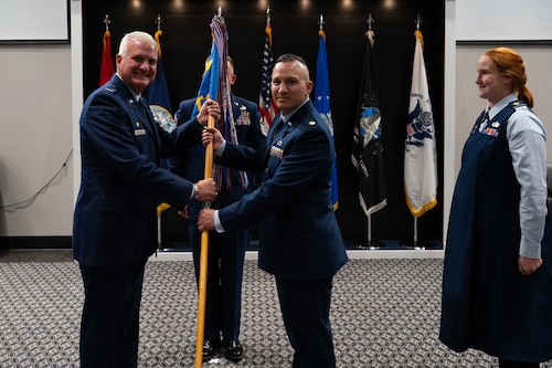 U.S. Air Force Col. Matthew Norton, 17th Training Wing commander, passes the 17th Comptroller Squadron guidon to Maj. Andrew Onderick, 17th CPTS commander, during a change of command ceremony at Goodfellow Air Force Base, Texas, June 2, 2026. Passing of the guidon is a long military tradition that represents the transfer of leadership responsibilities to the next commander. (U.S. Air Force photo by Senior Airman Brian Lummus)