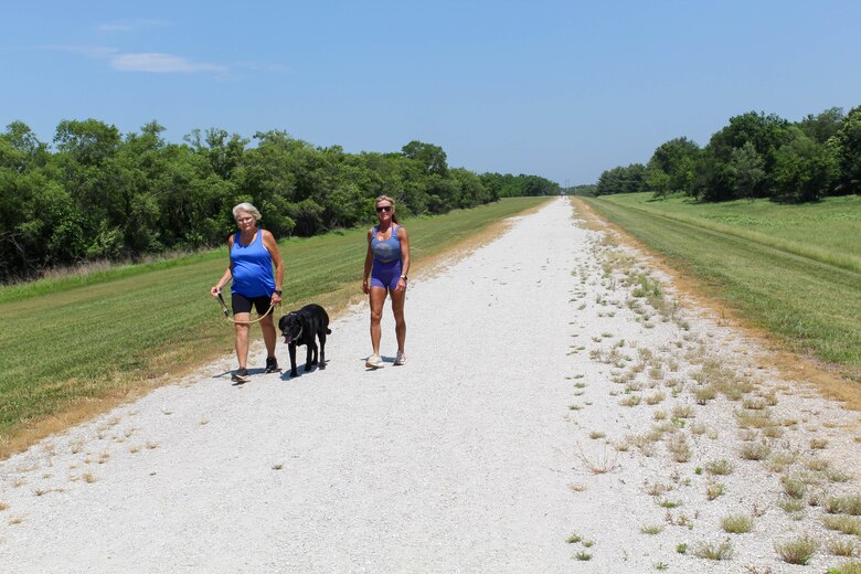 Women walking dog on trail.