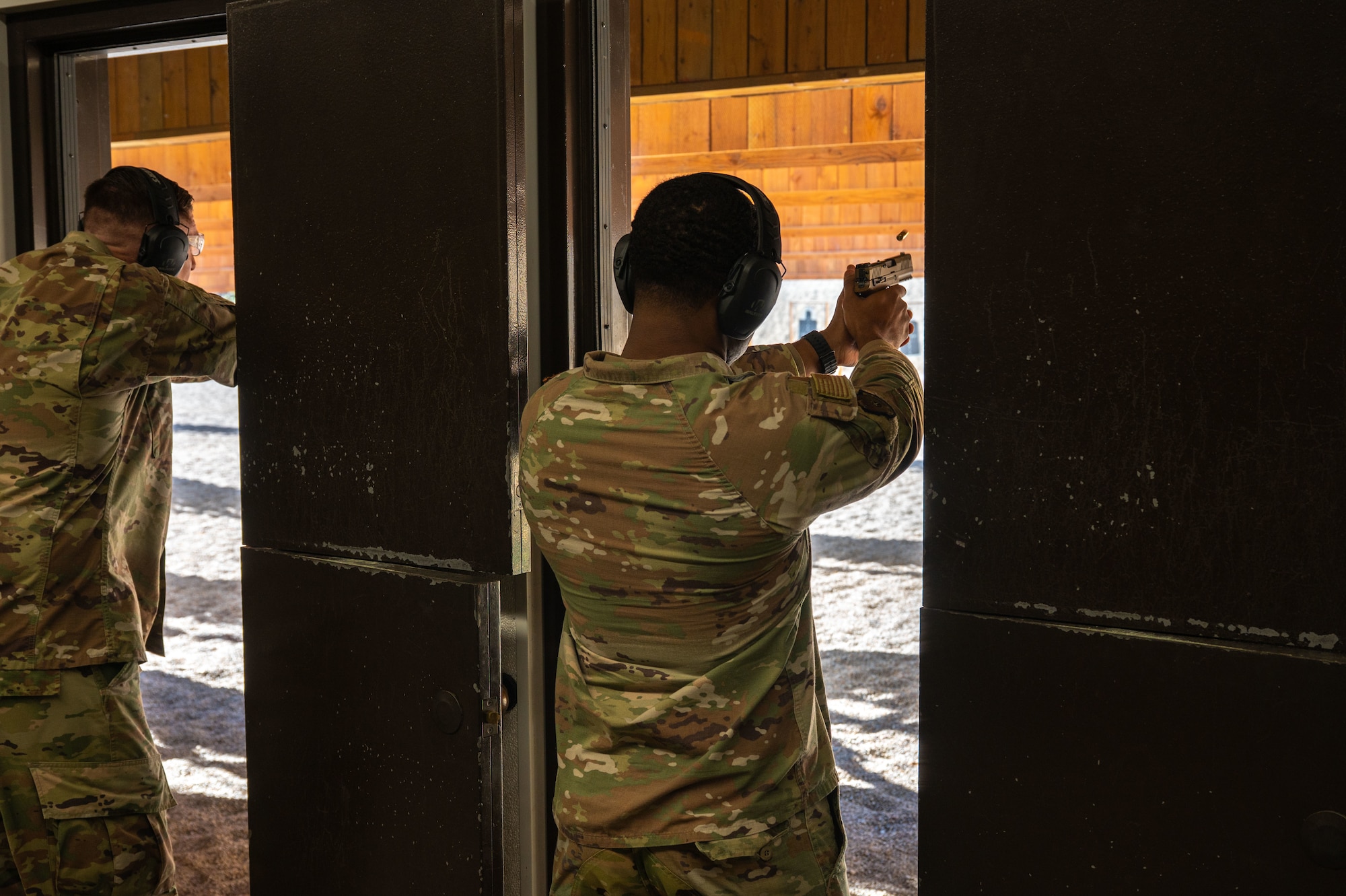 Airman fires a handgun at a firing range.