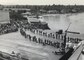 Black and white image of military members in a line boarding a ship.