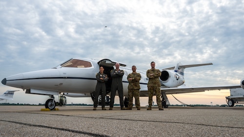 4 airmen standing in front of a jet with their arms crossed.