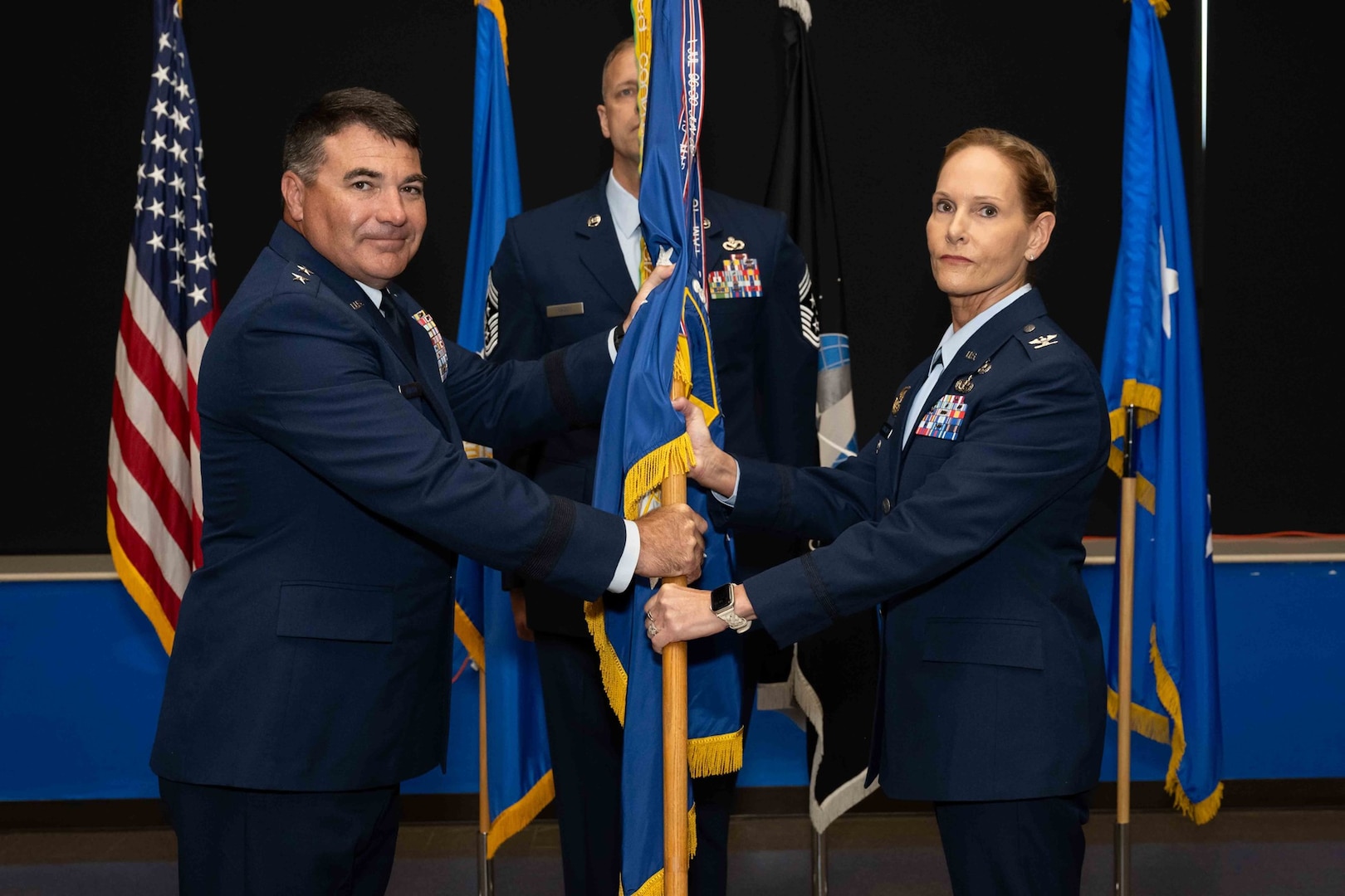 Air Force commander, passes the 37th Training Wing guidon to Col. Kellie S. Courtland, 37th TRW incoming commander, during the 37th TRW change of command ceremony at Joint Base San Antonio-Lackland, Texas, May 29, 2026. The change of command ceremony is a military tradition that allows unit members to see the outgoing commander depart and identify the incoming commander. (U.S. Air Force photo by Marcus Robins)