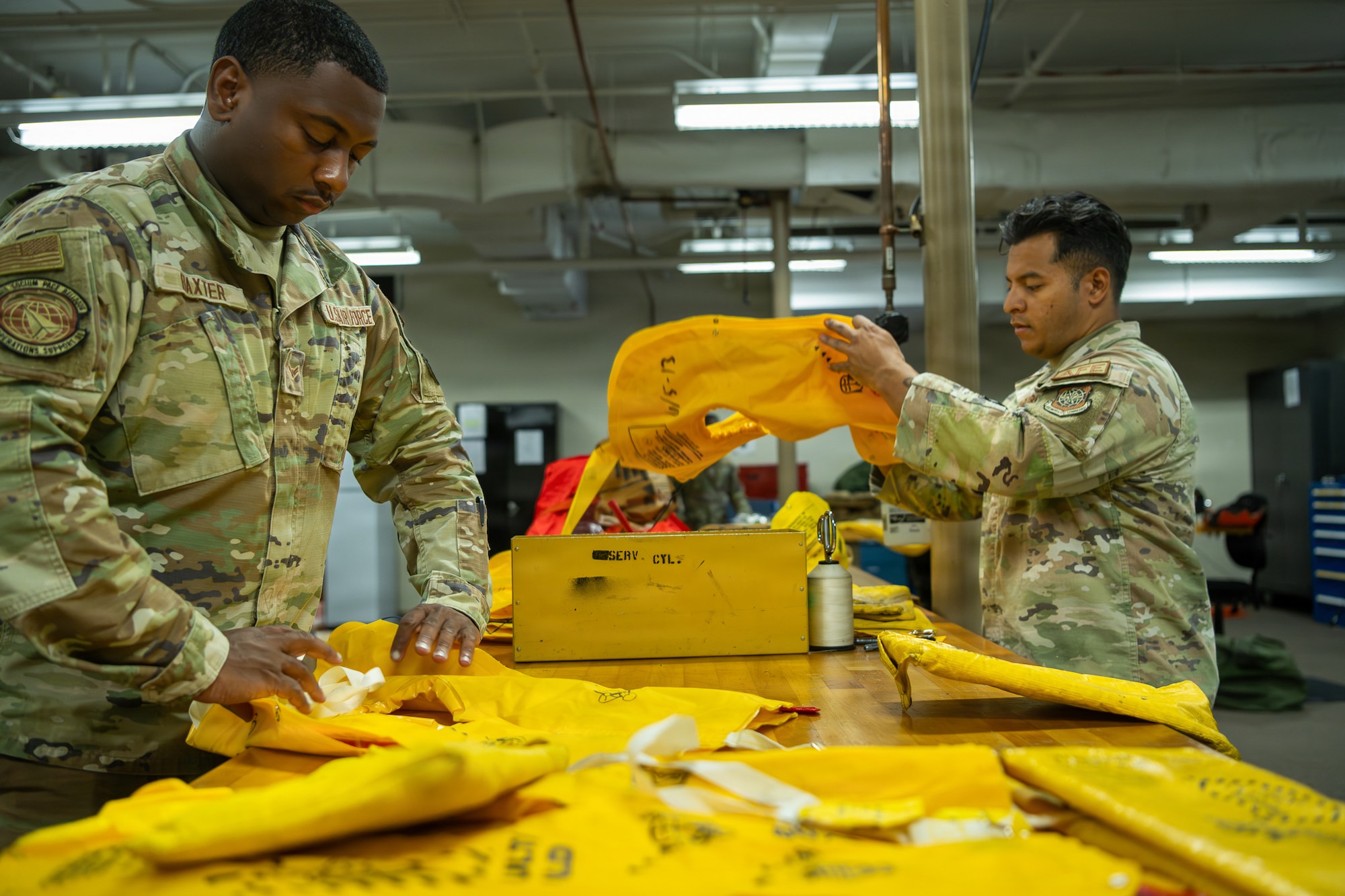 U.S. Air Force Airman 1st Class Giovanni Baxter, left, 6th Operation Support Squadron aircrew flight equipment journeyman, and Staff Sgt. Christian Mijia-Mendoza, 6th OSS aircrew flight equipment craftsman, inspect life preservers at MacDill Air Force Base, Florida, May 19, 2026. AFE technicians routinely inspect survival equipment to ensure it is operational and ready for use. (U.S. Air Force photo by Airman Micquill Davis)