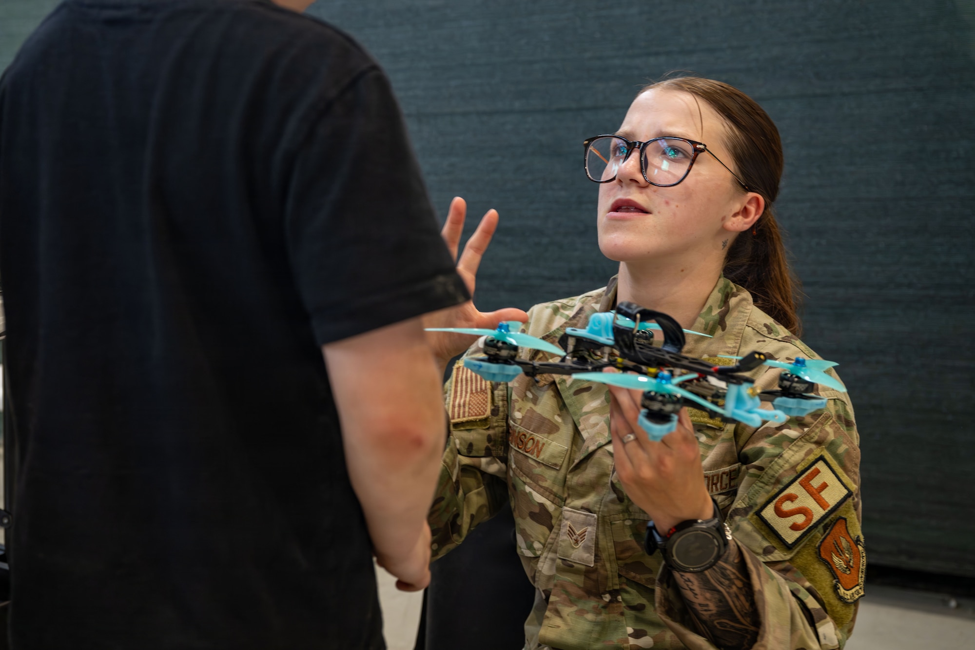 A woman holds a drone while talking to a child