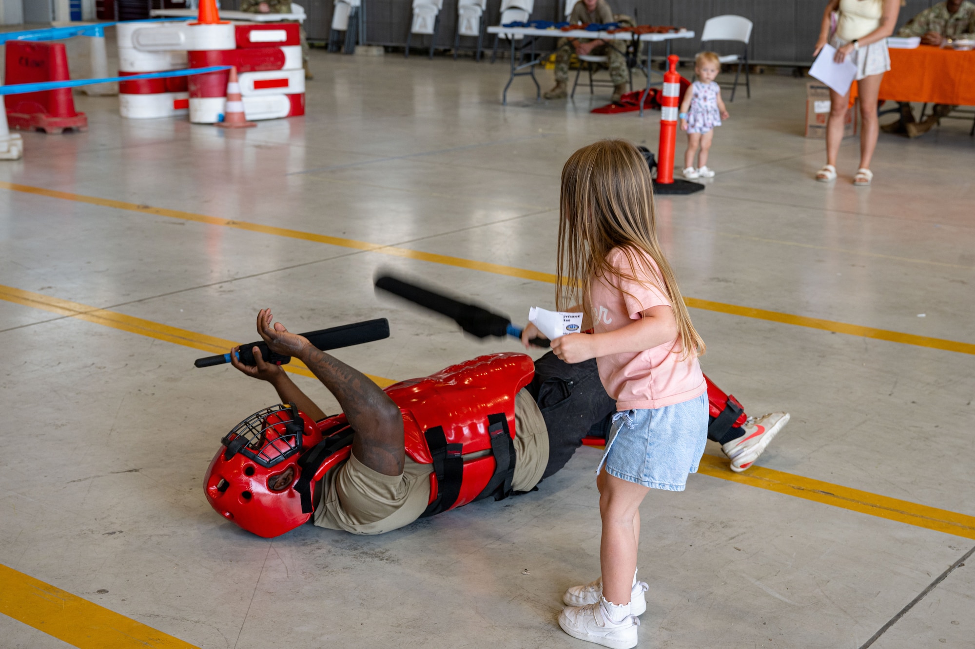 A child hits a man in a red suit with a stick