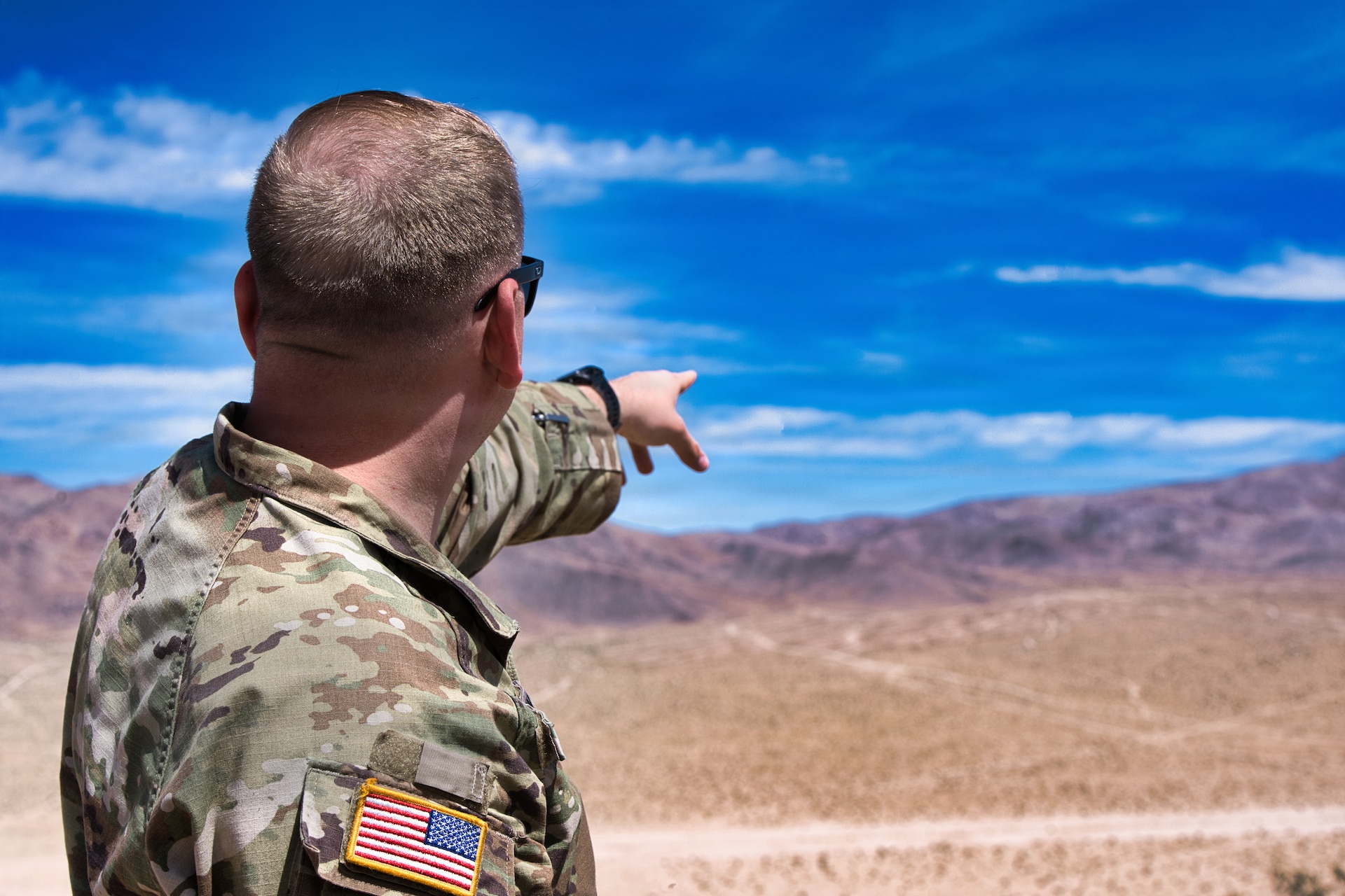 Sgt. 1st Class Daniel Drury points at the designated impact zone from atop the observation point during Exercise Arcane Thunder 26 at Fort Irwin, California, April 24, 2026.