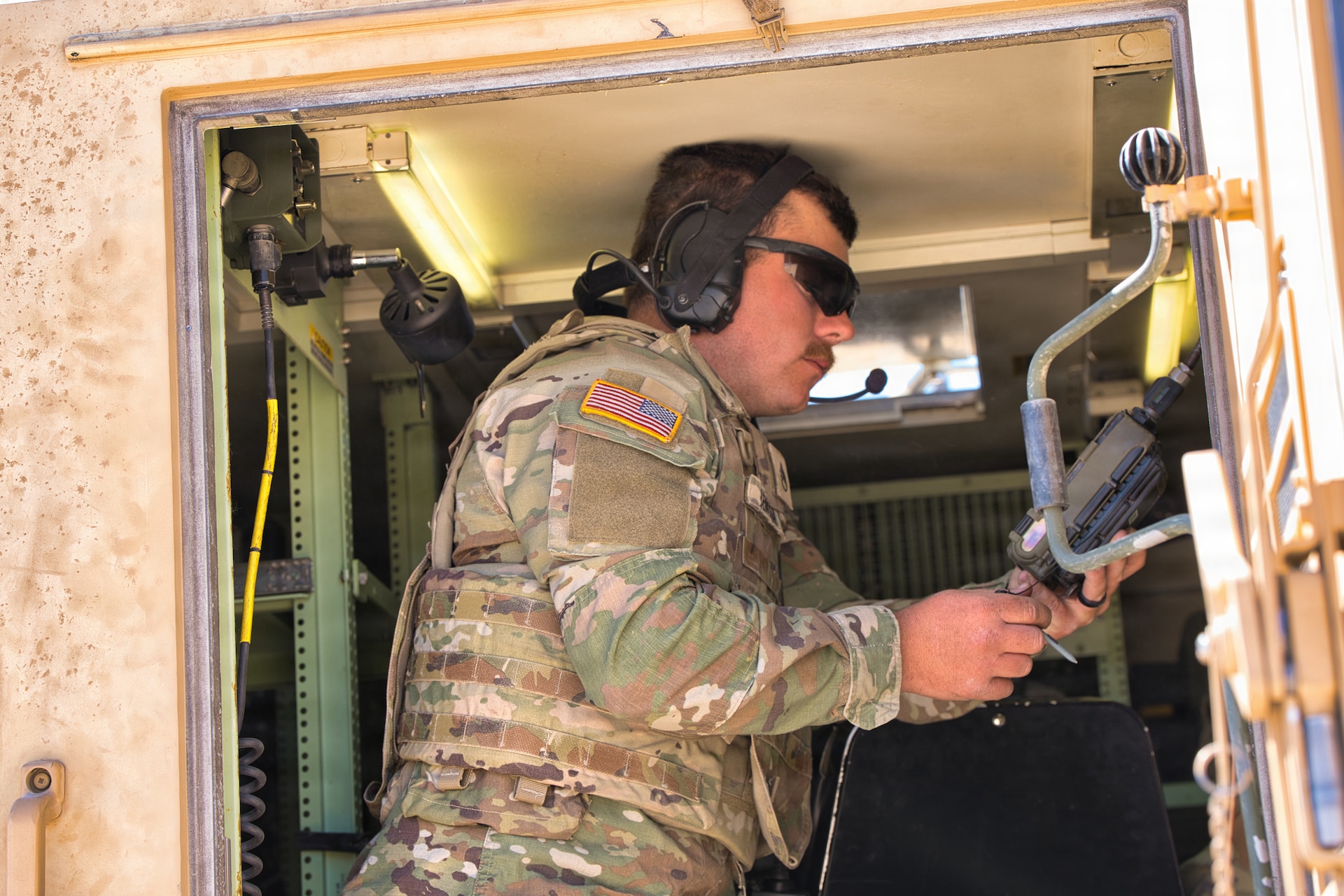 U.S. Army Staff Sgt. Derek Benham using a simple key loader to program radios while training during Exercise Arcane Thunder 26 at Fort Irwin, California, April 24, 2026.