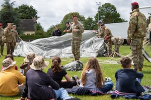 U.S. paratroopers assigned to the Light Support Battalion, 173rd Airborne Brigade, orient students from Picauville Elementary School to a parachute during a D-Day 82 exchange at Picauville, France, June 2, 2026. The 173rd Airborne Brigade joined representatives from the Golden Knights and the Round Canopy Parachute Team to orient French school children to paratrooper equipment. (U.S. Army photo by Maj. Joe Legros)