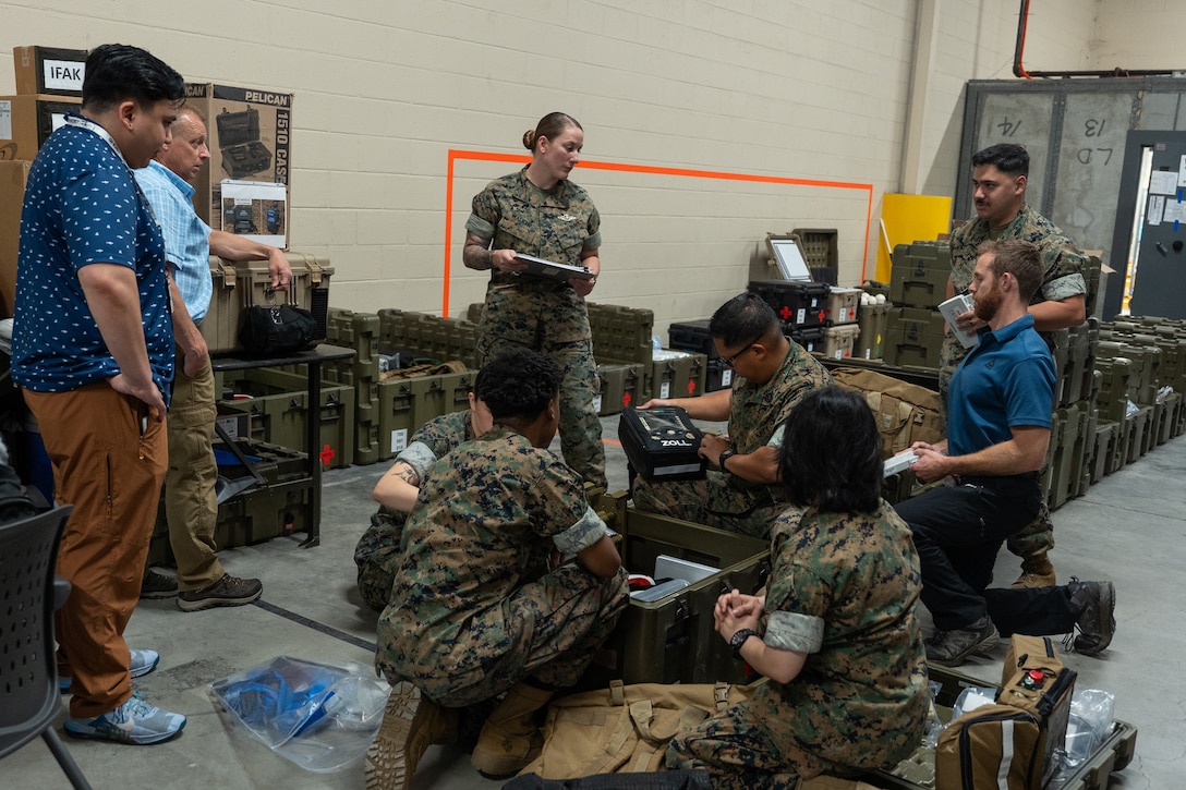 Sailors and civilians standing around containers with medical equipment