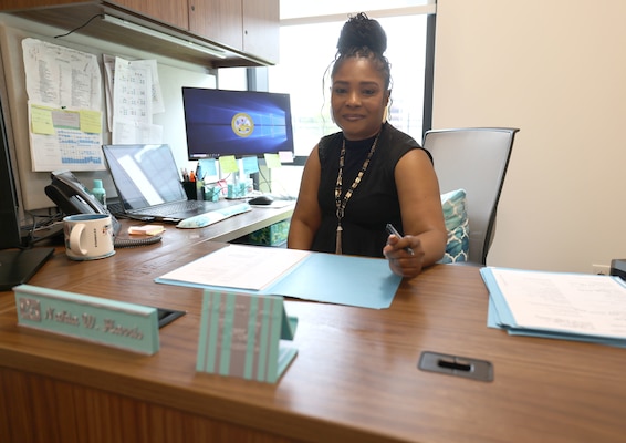 Picture of a woman sitting at a desk looking over some papers.