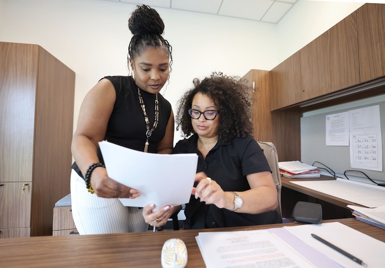 Picture of two women at a desk looking over some papers.