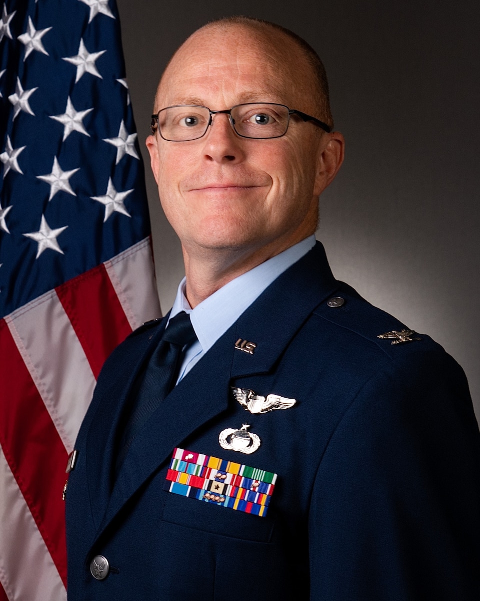 Official portrait of Col. Paul A. Pedersen in service dress uniform with U.S. flag draped behind right shoulder