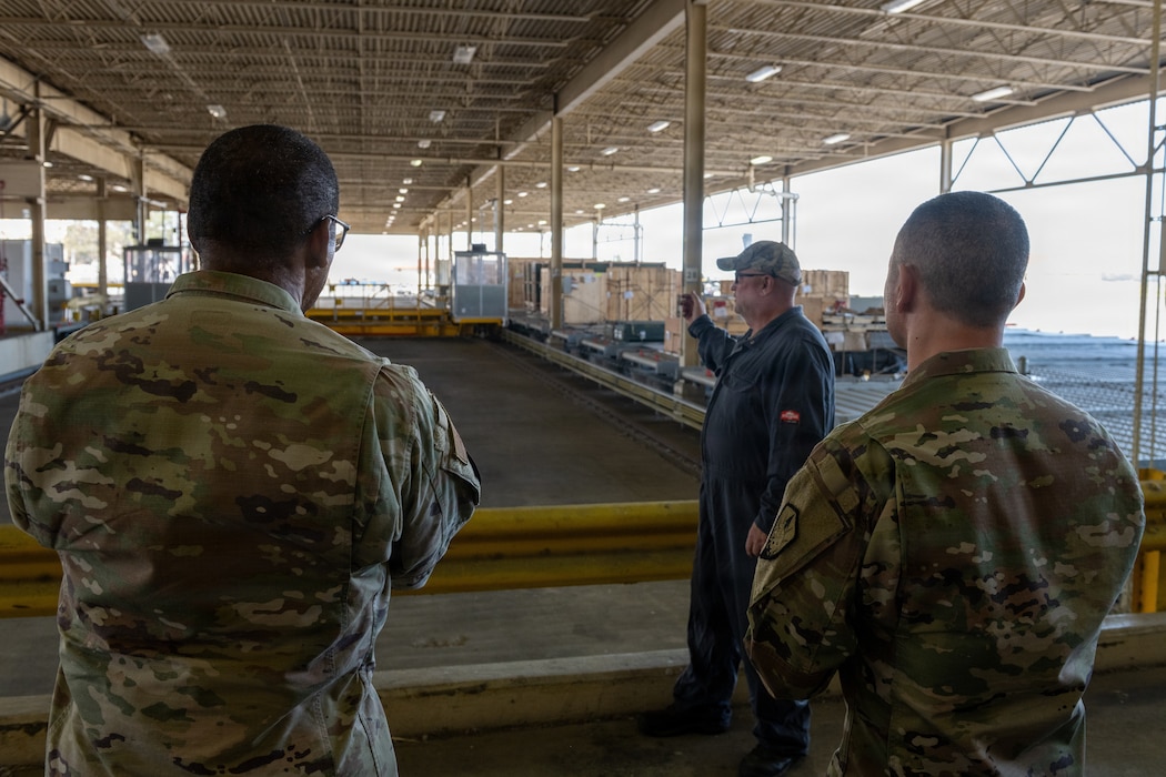 Worker explaining outside dock to USTRANSCOM commander and chief