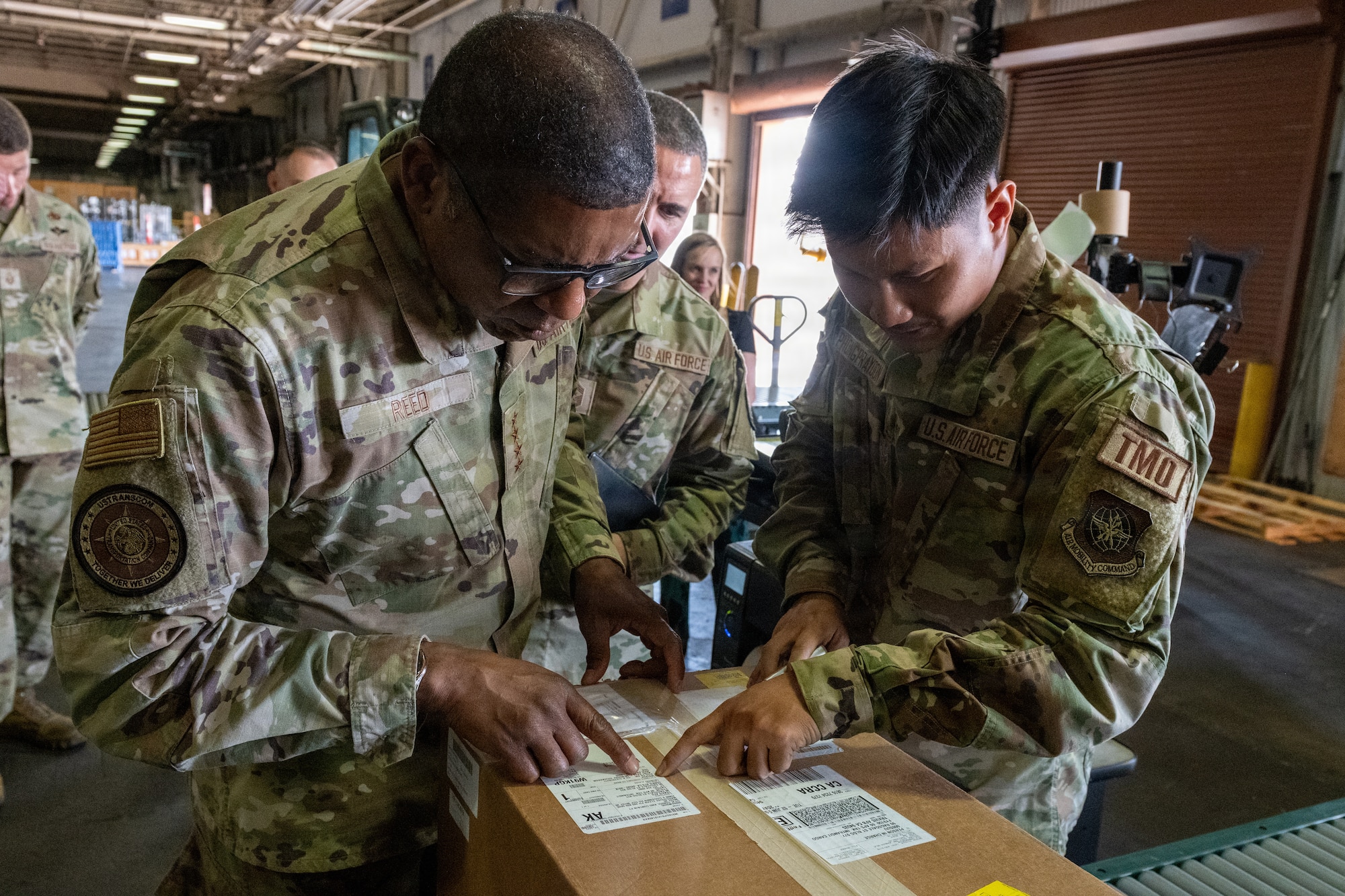 USTRANSCOM commander reads label on box with Airman