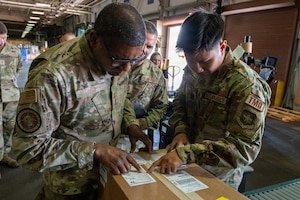 USTRANSCOM commander reads label on box with Airman
