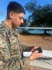 U.S. Marine Corps Sgt. Christian Hanna, a data systems administrator assigned to15th Marine Expeditionary Unit, I Marine Expeditionary Force, reviews tactical data on a cell phone running the Tactical Assault/Team Awareness Kit (TAK) outside the Exercise Cobra Gold 2026 Combined Joint Force Maritime Coordination Center, Royal Thai Marine Corps Base Camp Jessada, Chonburi, Thailand, March 2, 2026.