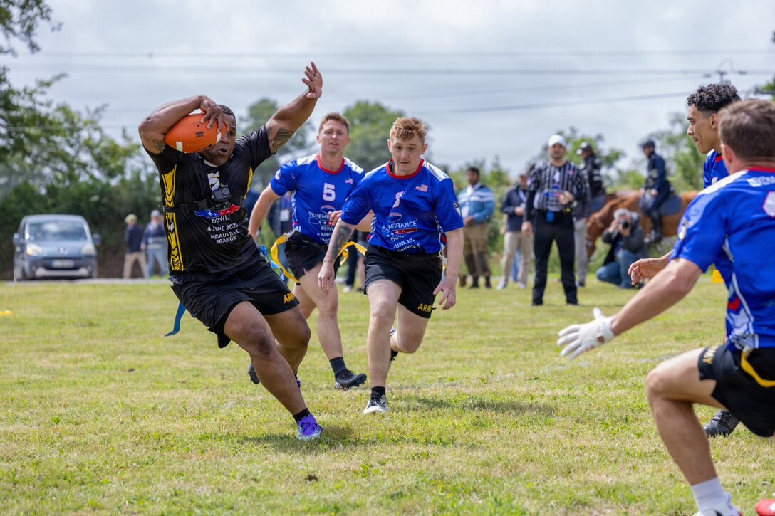 People in athletic gear play football in a field.