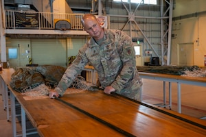 An Airman rigs a parachute on a table.