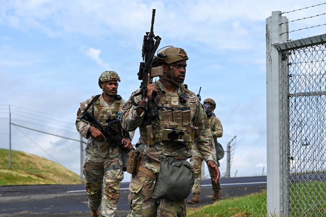 U.S. military members walk will holding a weapon.