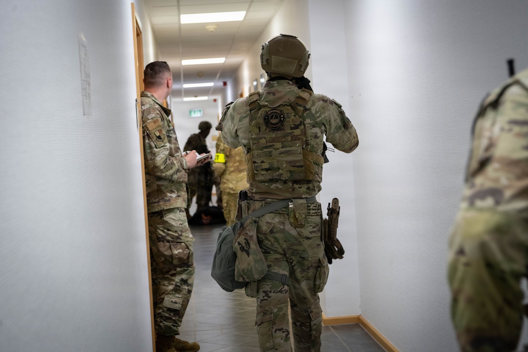 A U.S. Air Force Airmen walks down the hallway while holding a weapon.
